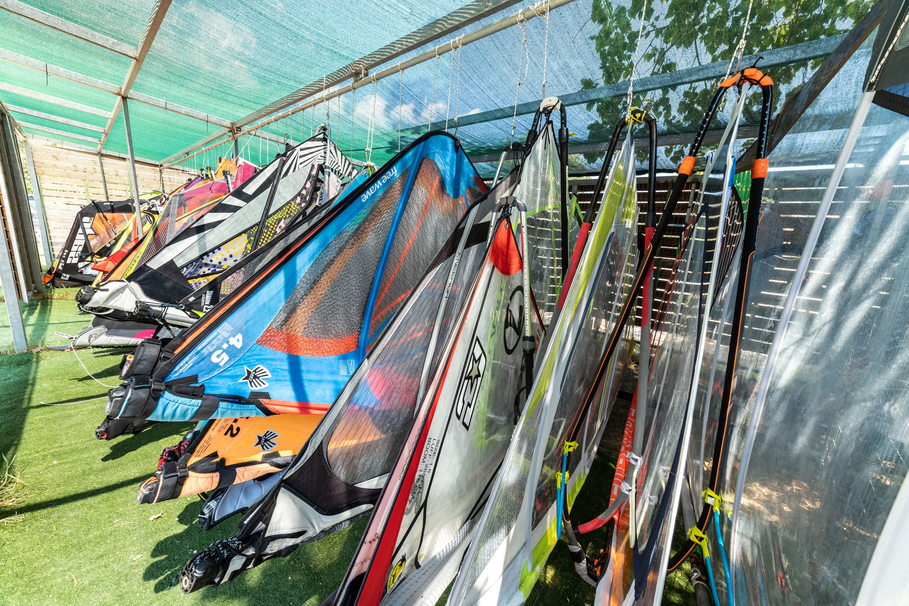 A row of windsurfing boards under a covered area.