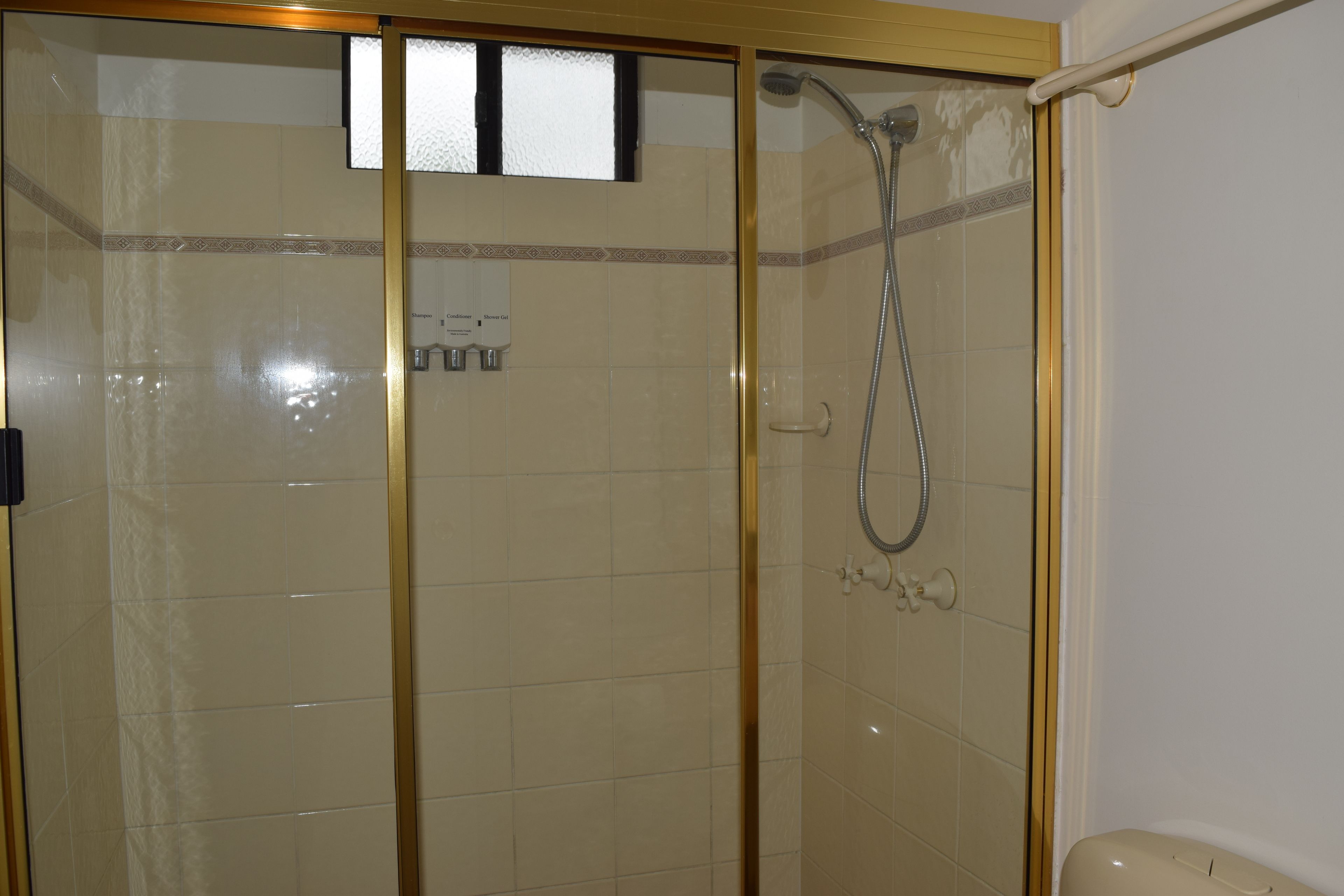 Een douchecabine van glas met een handdouche en een bedieningspaneel aan de muur.