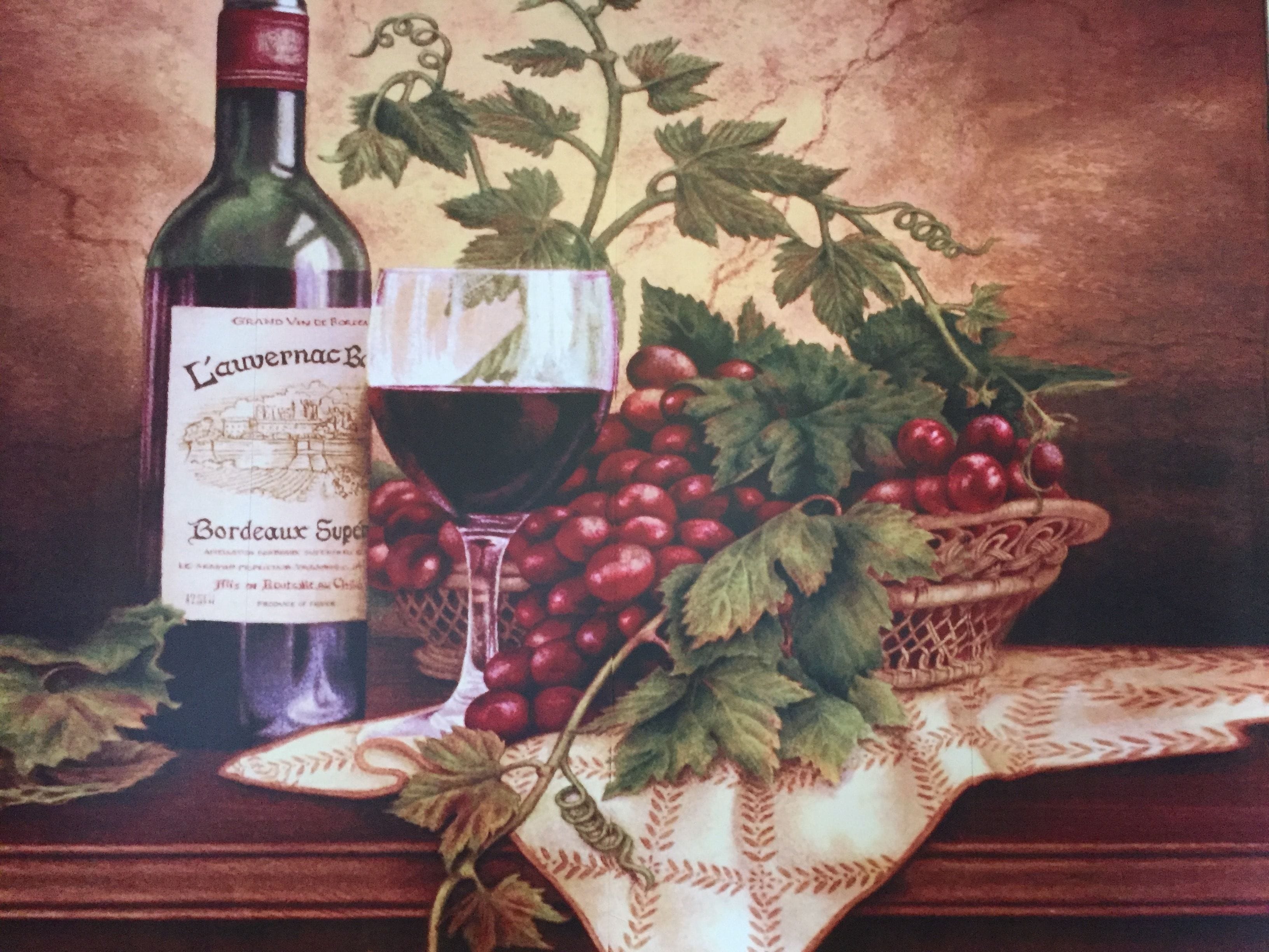 Una botella de vino, una copa de vino tinto y una cesta de uvas rojas.