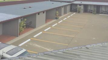 Un estacionamiento con una hilera de edificios de una planta, cada uno con una zona de estar al aire libre techada.