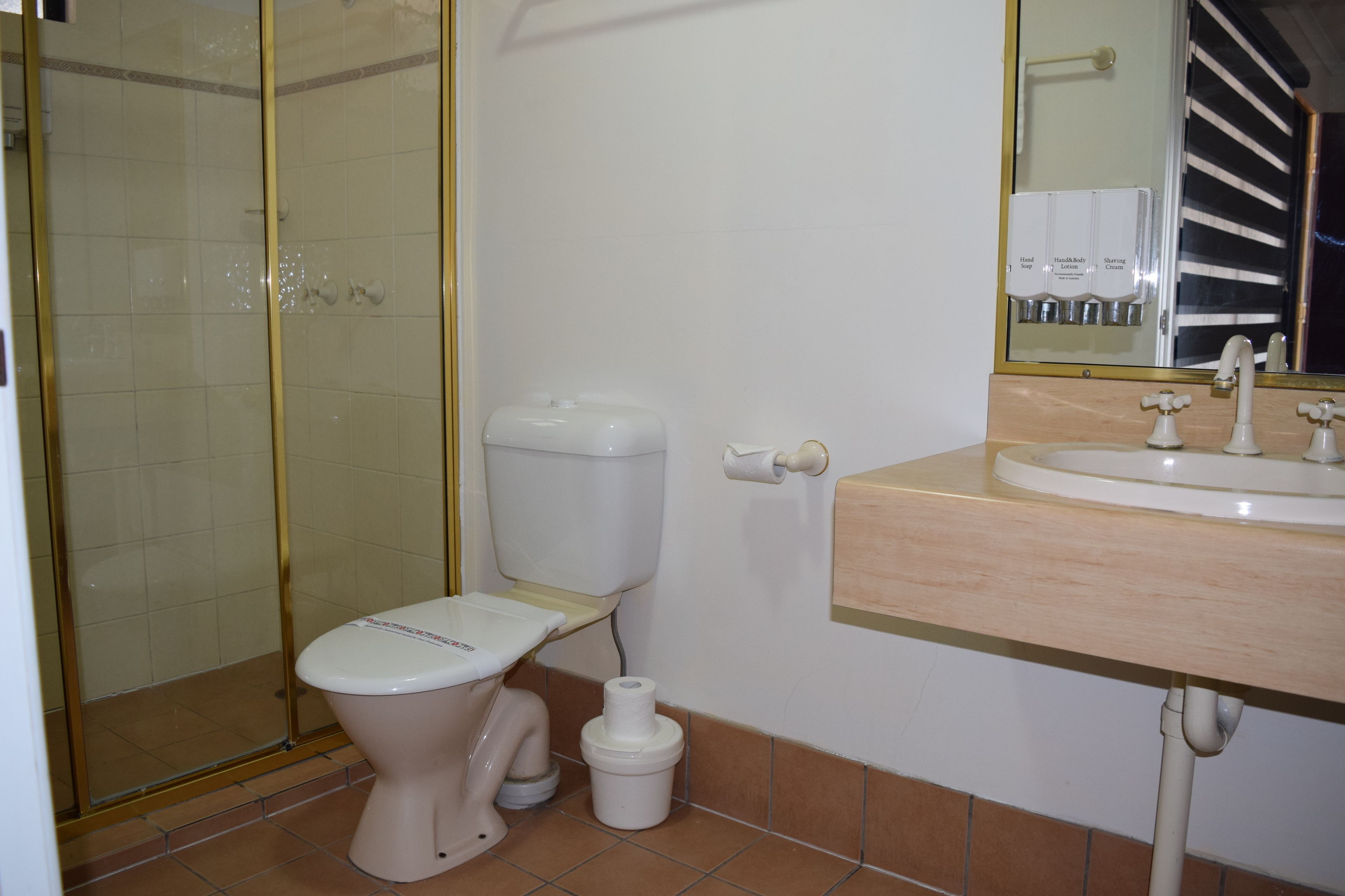 Un baño con inodoro, cabina de ducha y lavamanos con espejo.