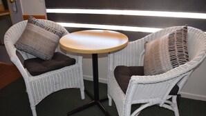 Two white wicker chairs with dark cushions and a small round table with a light-colored top. - Warwick Vines Motel (Warwick)