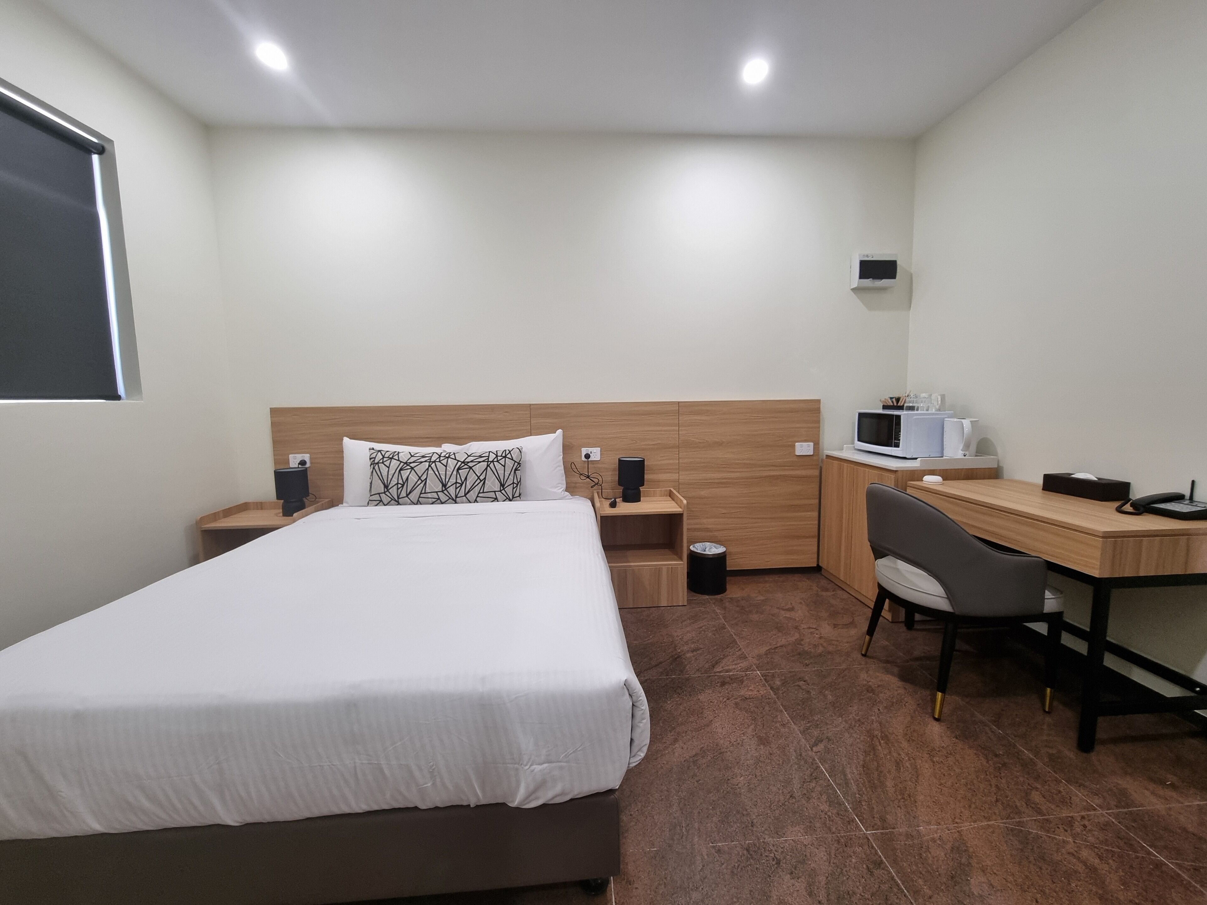 Une chambre d’hôtel équipée d’un lit, d’une table de chevet, d’un bureau, d’une chaise et d’un four à micro-ondes.