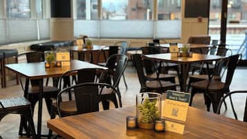 A restaurant interior with wooden tables and black chairs, featuring QR codes for digital menus and a sign indicating a non-alcoholic option.