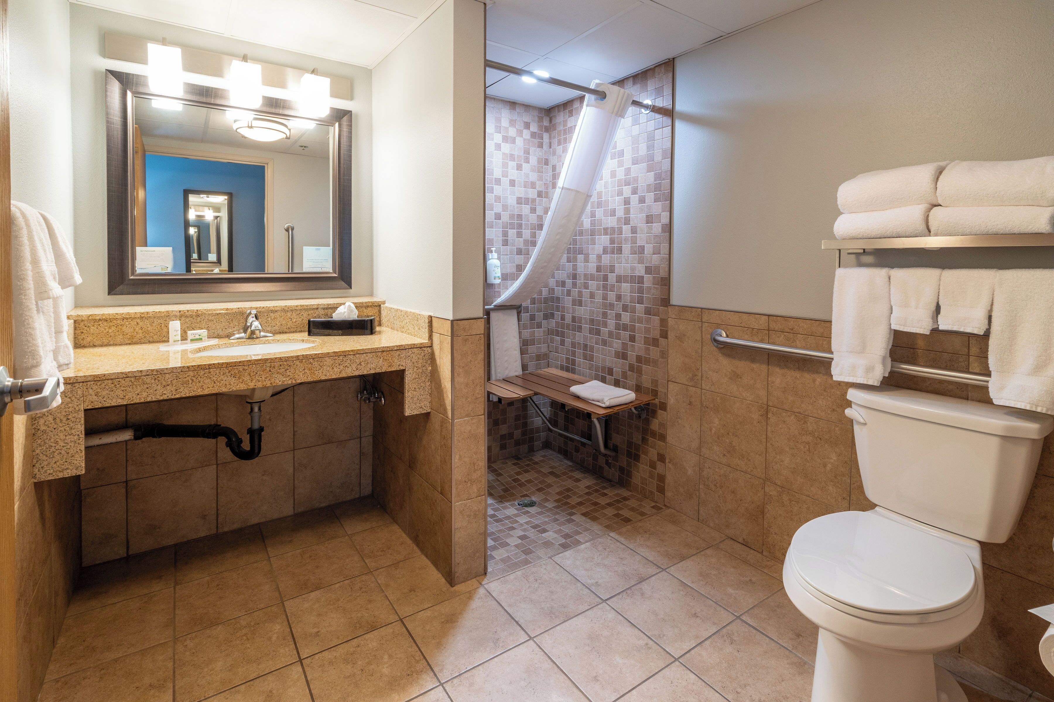 A bathroom with a sink, mirror, toilet, and shower area.