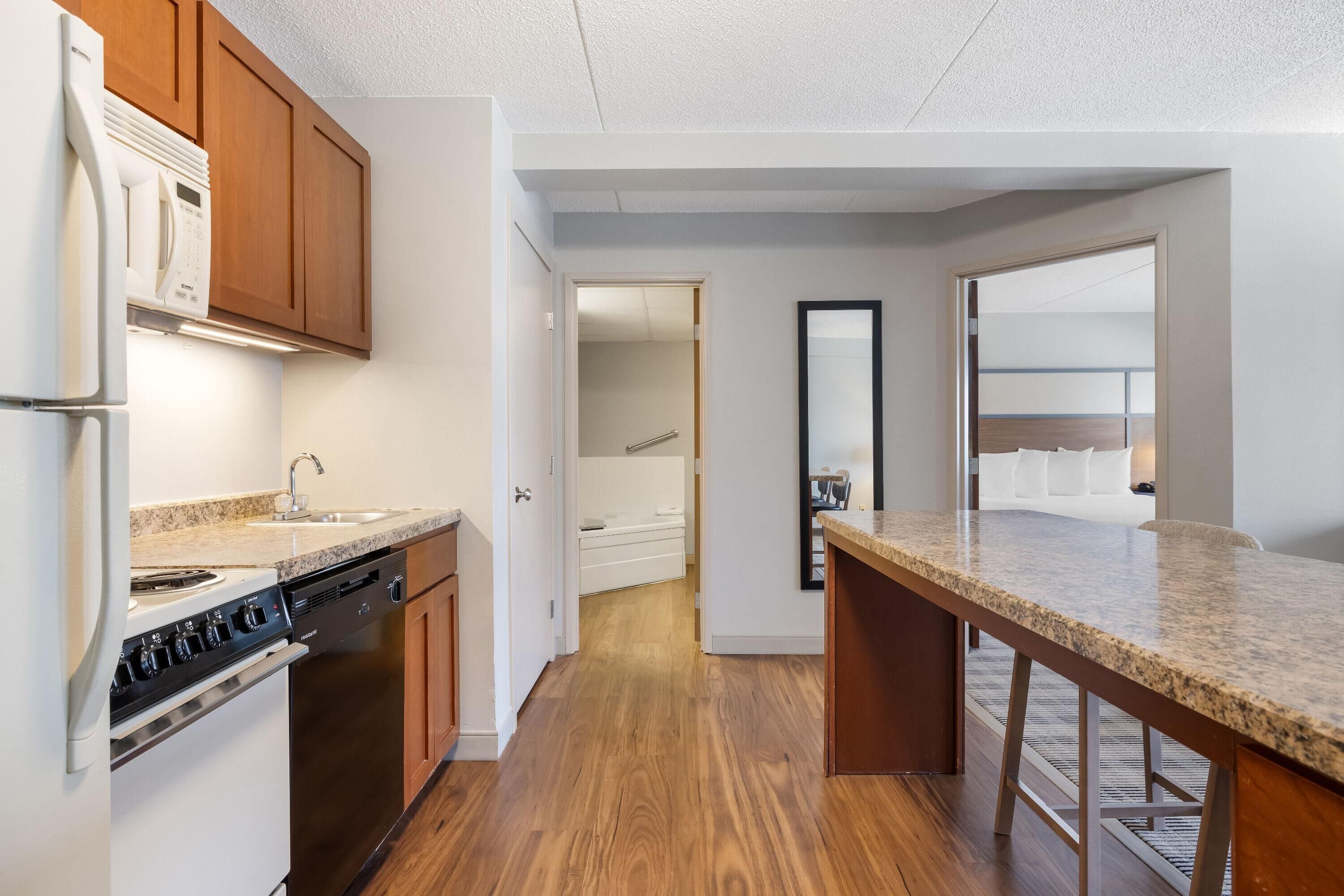 A modern kitchen with wooden cabinets, a built-in oven, and a granite countertop.