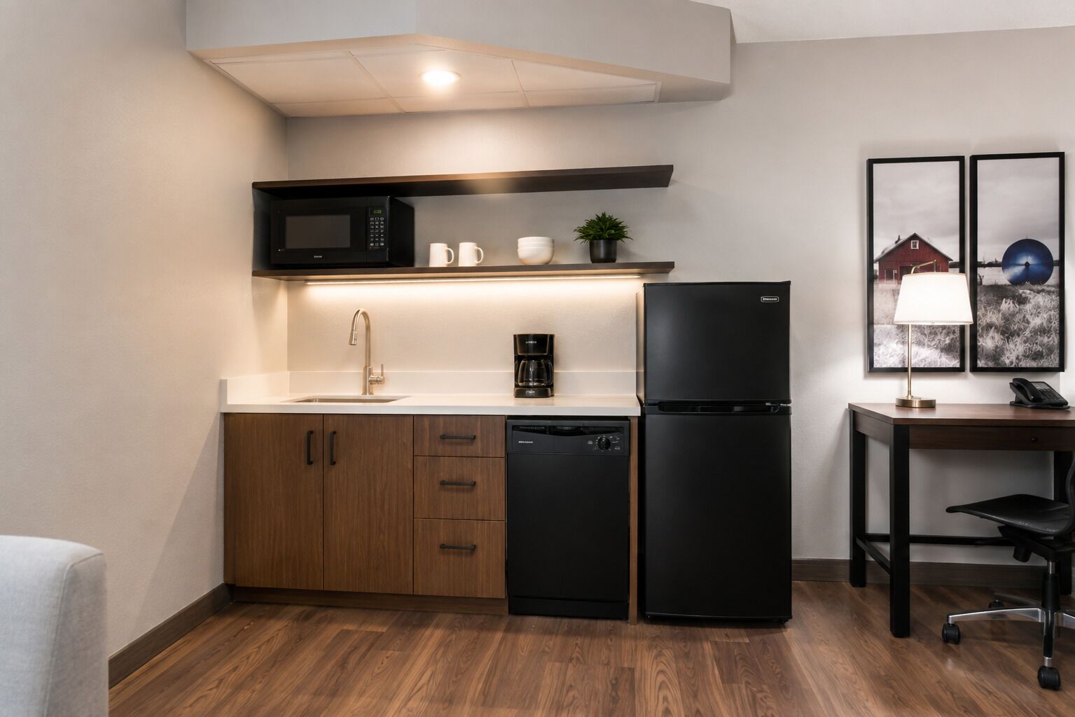 Una cocina compacta con microondas, cafetera y refrigerador.