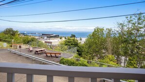 A view from a balcony overlooking a beach with a fence, picnic tables, and a distant lighthouse. - Quality Inn Port Angeles - near Olympic National Park (Port Angeles)