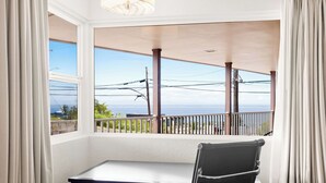 A room with a desk and chair, large windows with curtains, a view of the sea, and a balcony with a railing. - Quality Inn Port Angeles - near Olympic National Park (Port Angeles)