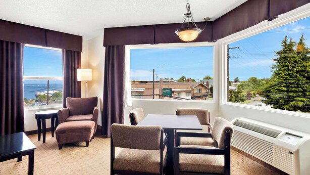 A hotel room with a large window, a table, two chairs, a lamp, and a ceiling light. - Quality Inn Port Angeles - near Olympic National Park (Port Angeles)