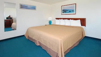 A hotel room with a large bed, a nightstand, a lamp, and two framed pictures on the wall.