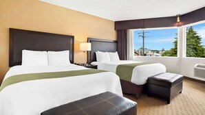 A hotel room with two beds, a small table, a lamp, and a window with a view of the outside. - Quality Inn Port Angeles - near Olympic National Park (Port Angeles)