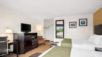 A hotel room with a bed, a desk with a computer, a television, a chair, and a dresser.