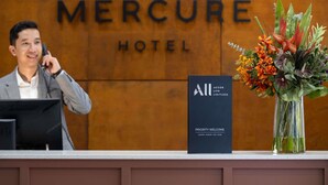 A hotel reception desk with a sign reading 'MERCURE HOTEL' and a 'PRIORITY WELCOME' sign. - Mercure Newcastle (Newcastle West)