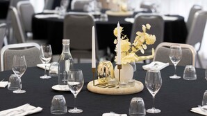 A dining table set with wine glasses, a bottle, and a centerpiece with candles and flowers. - Mercure Newcastle (Newcastle West)