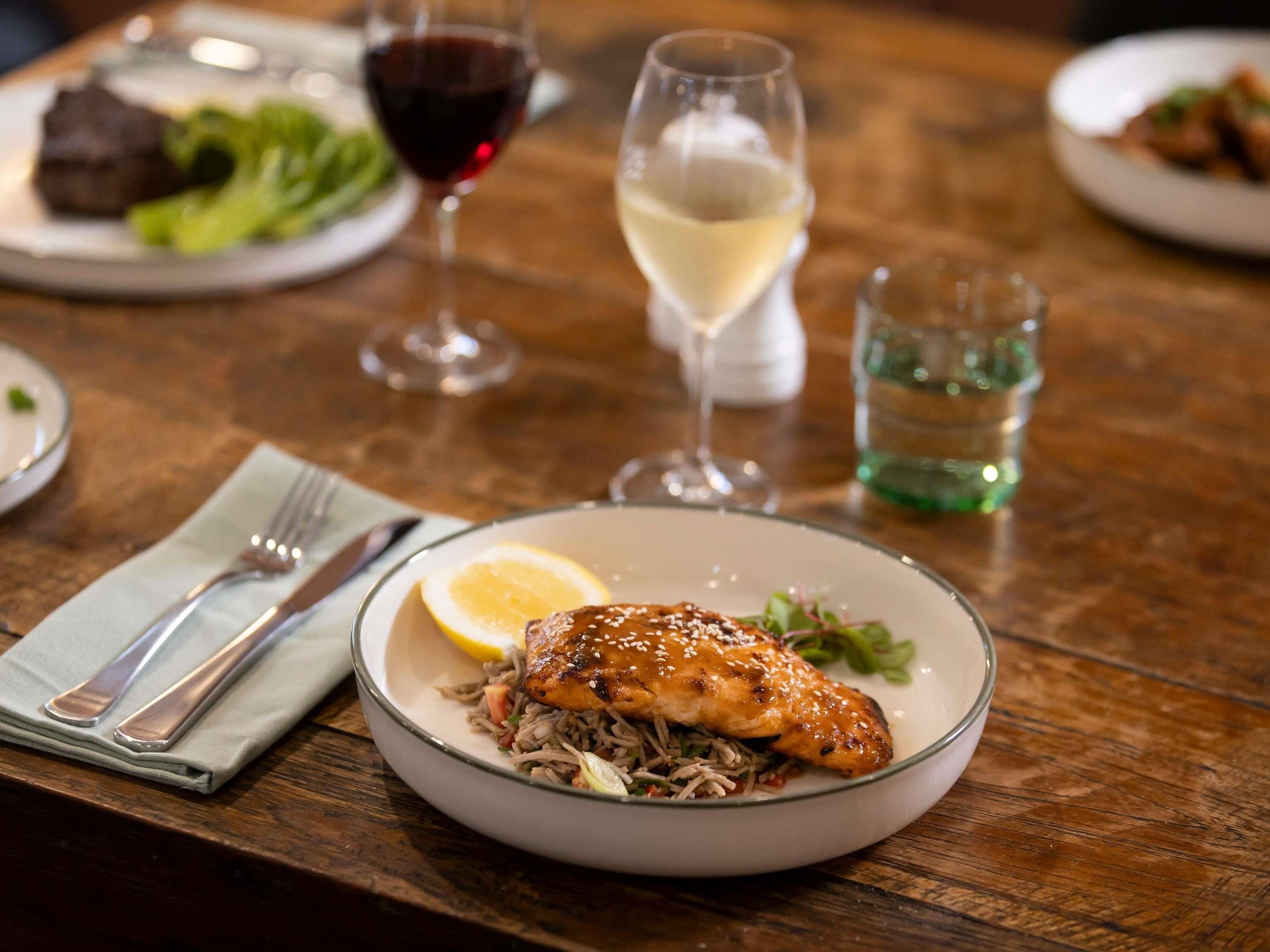 A dining table with a plate of food, a glass of white wine, and a glass of red wine.