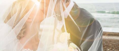 A couple embracing with a beach view in the background.