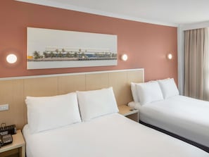 A hotel room with two beds, a painting on the wall, and a nightstand with a phone and a remote control. - Mercure Newcastle (Newcastle West)