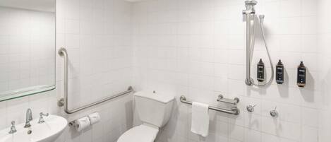 Une salle de bain avec un lavabo, des toilettes et une douche, le tout de couleur blanche.