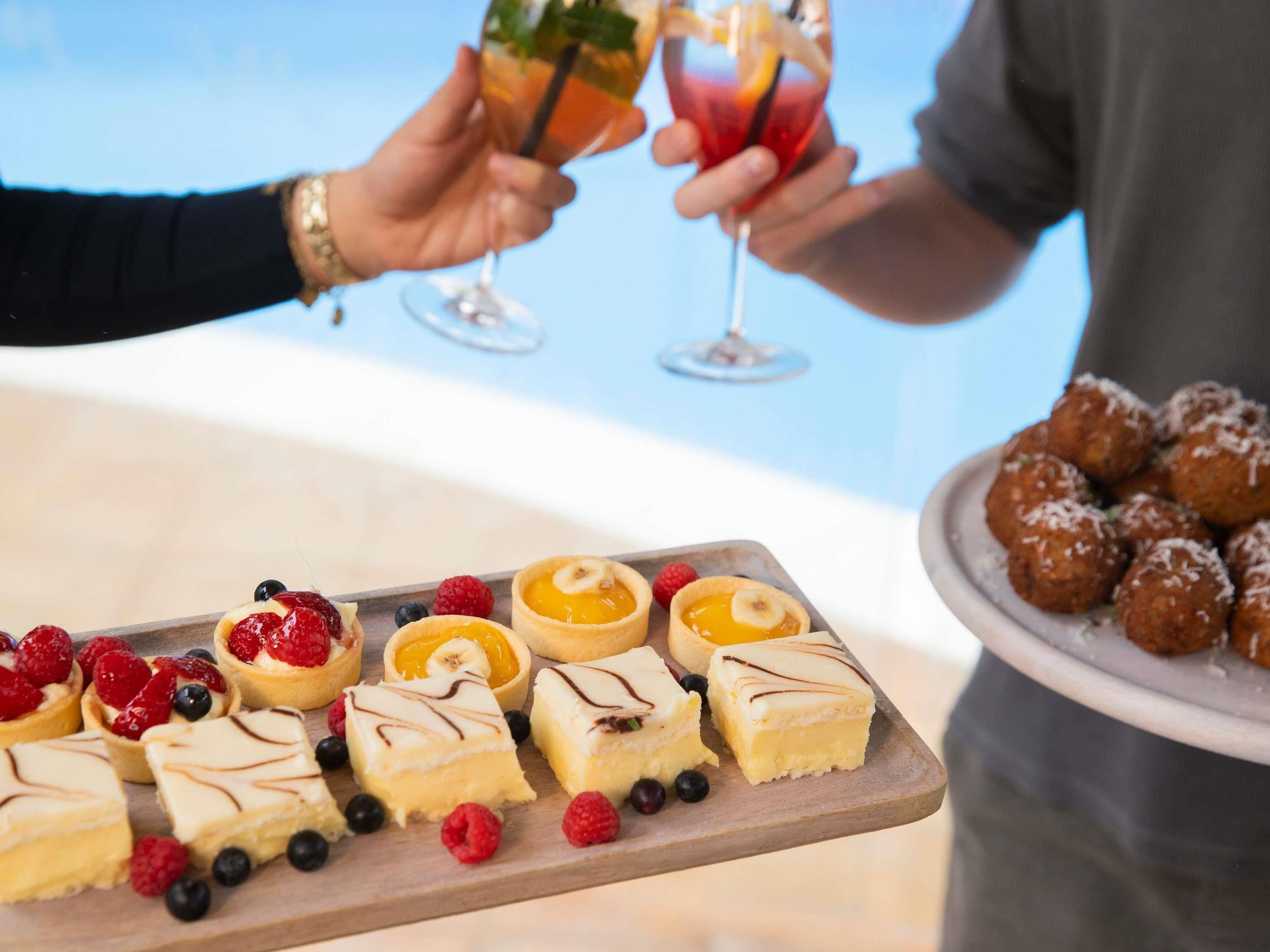 A dessert tray with various pastries and a plate of meatballs.