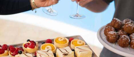 A dessert tray with various pastries and a plate of meatballs.