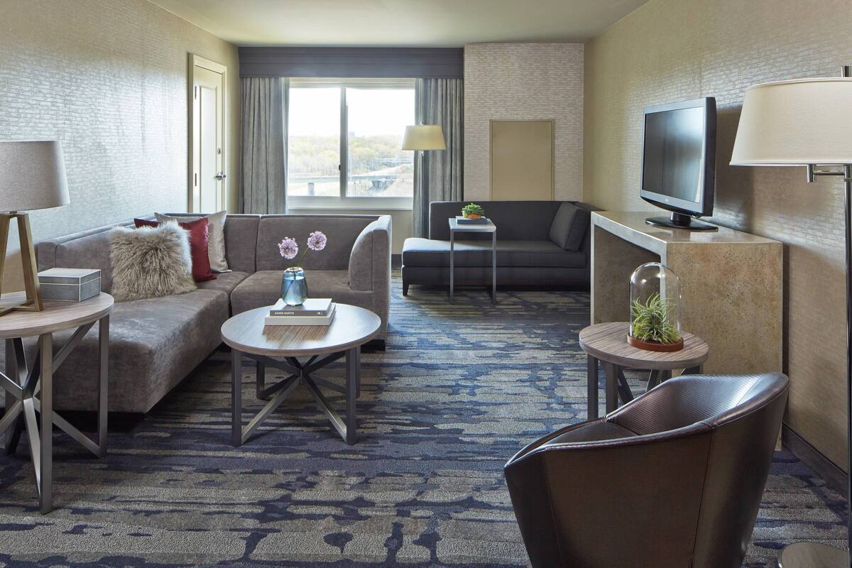 A hotel room with a sofa, a coffee table, a TV, and a lamp.