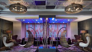 A modern lobby with a central seating area, a decorative tree, and ambient lighting.