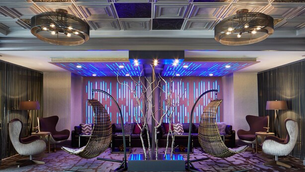 Un hall d’entrée moderne avec un espace salon central, un arbre décoratif et un éclairage d’ambiance.