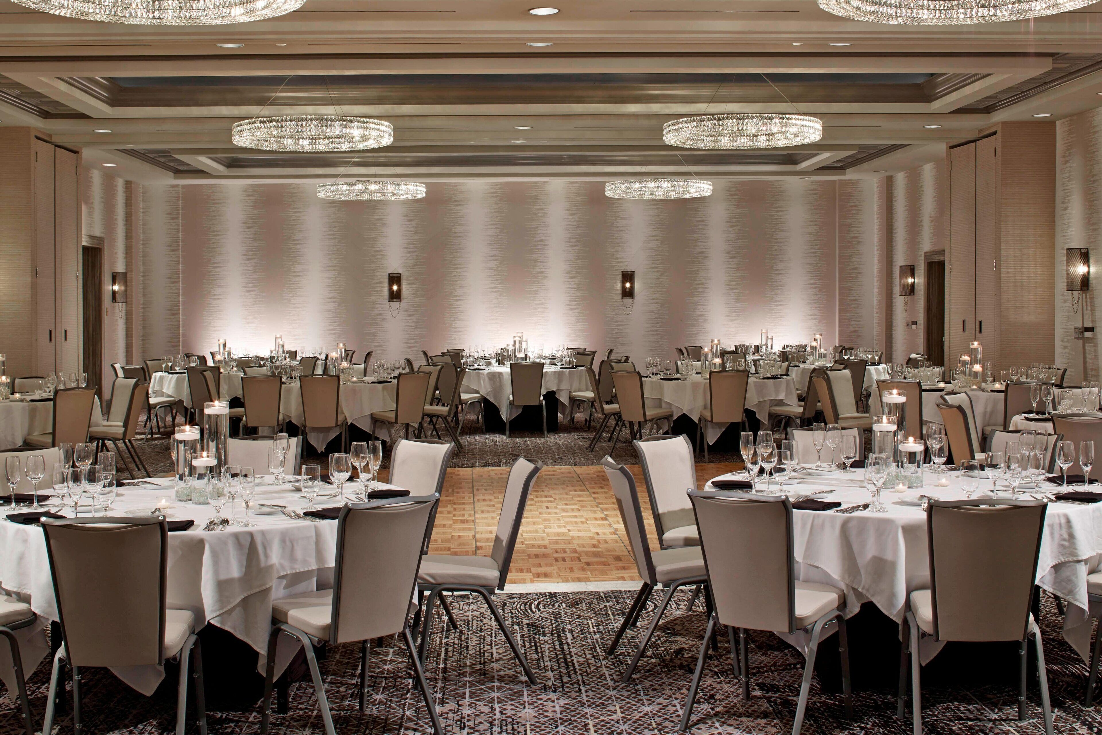 Un amplio salón de banquetes con varias mesas redondas dispuestas para comer, cada una con mantel blanco y sillas.