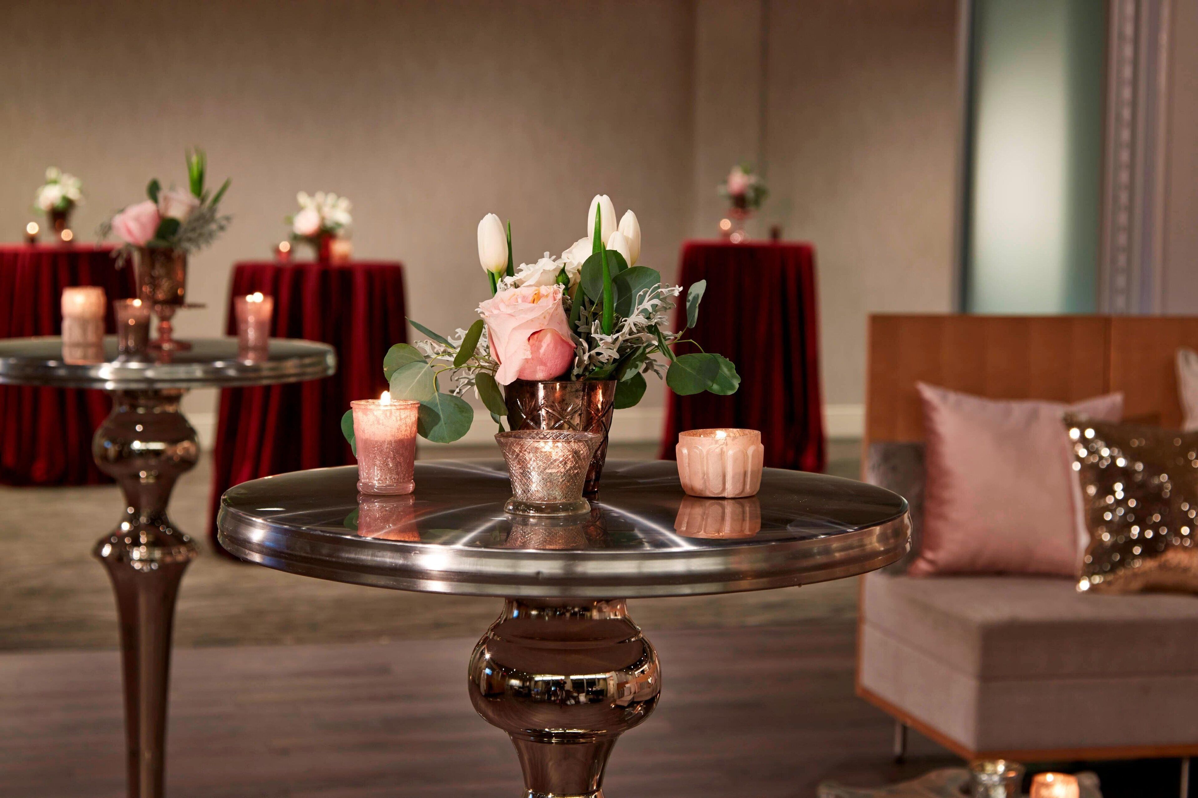 Une salle avec des tables rondes, chacune décorée de bougies et d’arrangements floraux.