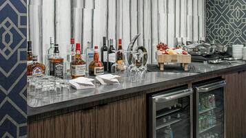 Eine moderne Bar mit einer Marmorplatte, verschiedenen Spirituosenflaschen, Gläsern und einer Obstschale.