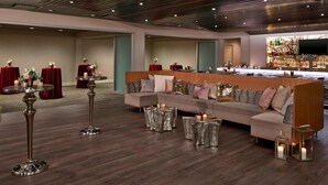 Un espace de détente moderne avec un long canapé, des tables rondes et un bar.