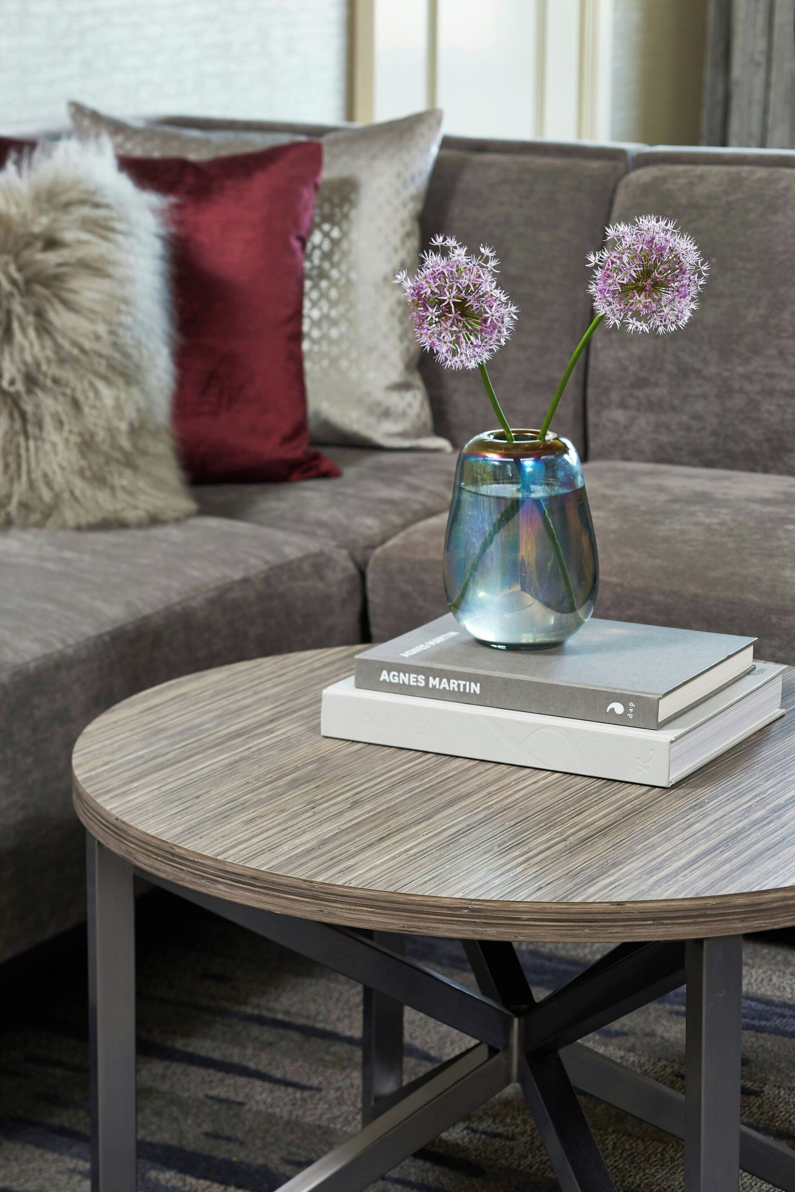 A round table with a book titled "AGNES MARTIN" and a vase with flowers.