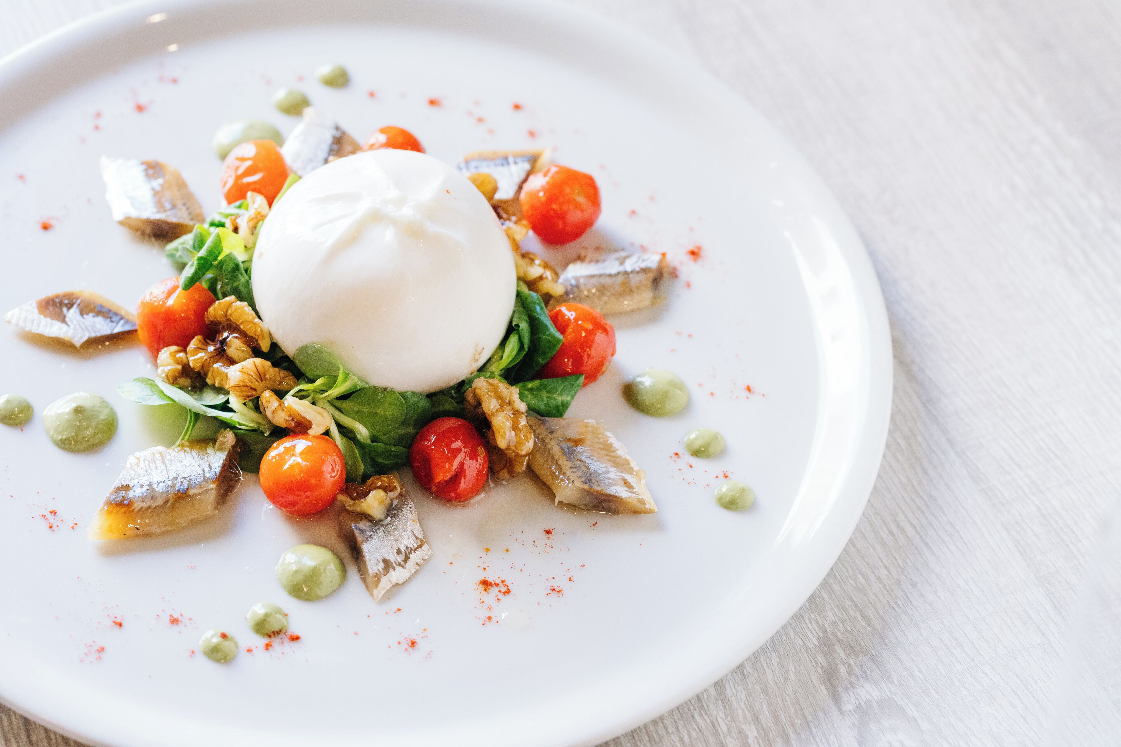 A white plate with a poached egg, cherry tomatoes, and green peas.