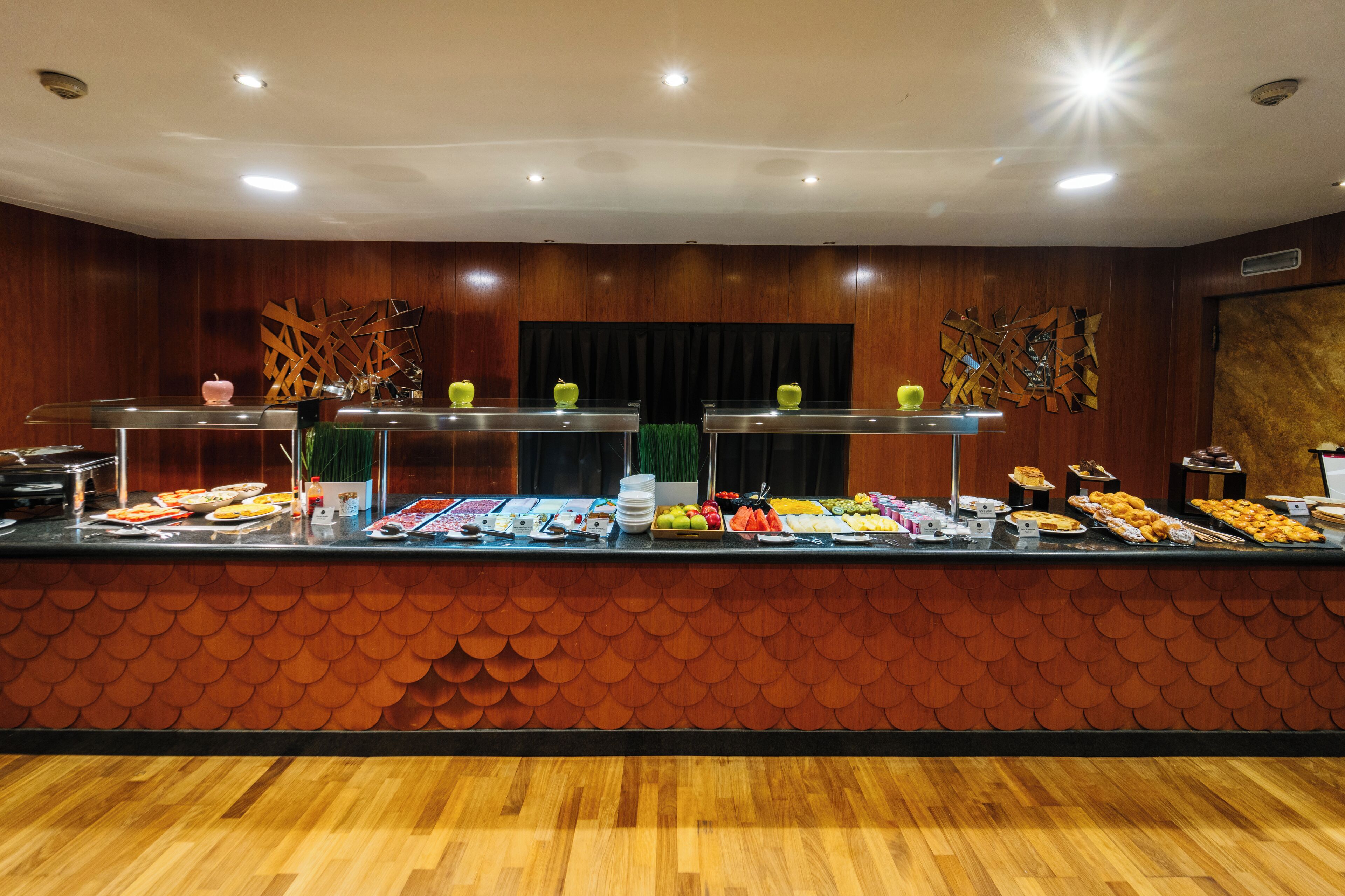 A buffet with various food items and a decorative wall with a scalloped pattern.