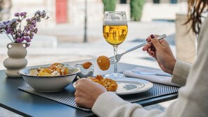 Una mesa de comedor con un bol de comida, una copa de vino y un jarrón de flores.