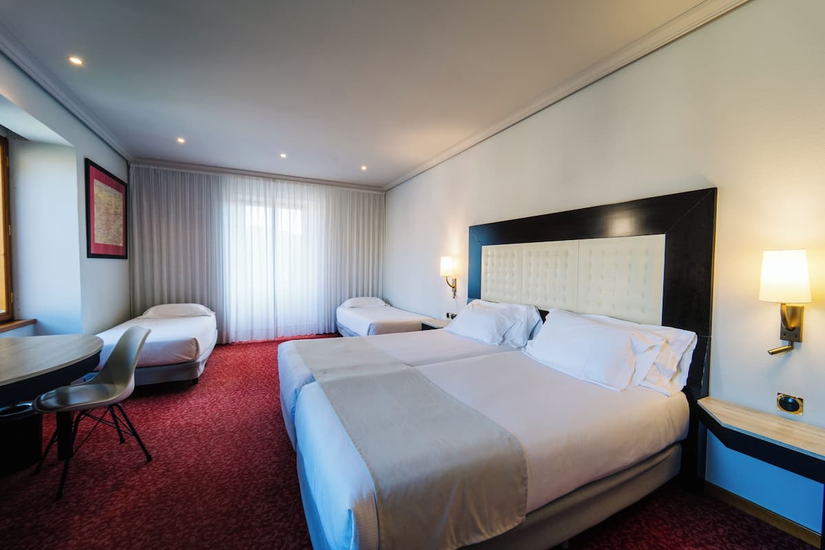 Une chambre d’hôtel avec deux lits, un bureau et une chaise.