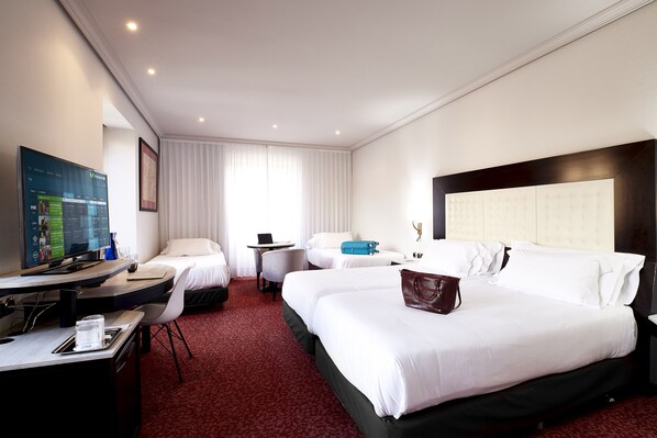 A hotel room with two beds, a desk with a computer, a TV, and a large window with curtains. - Abba Fonseca Hotel (Salamanca)