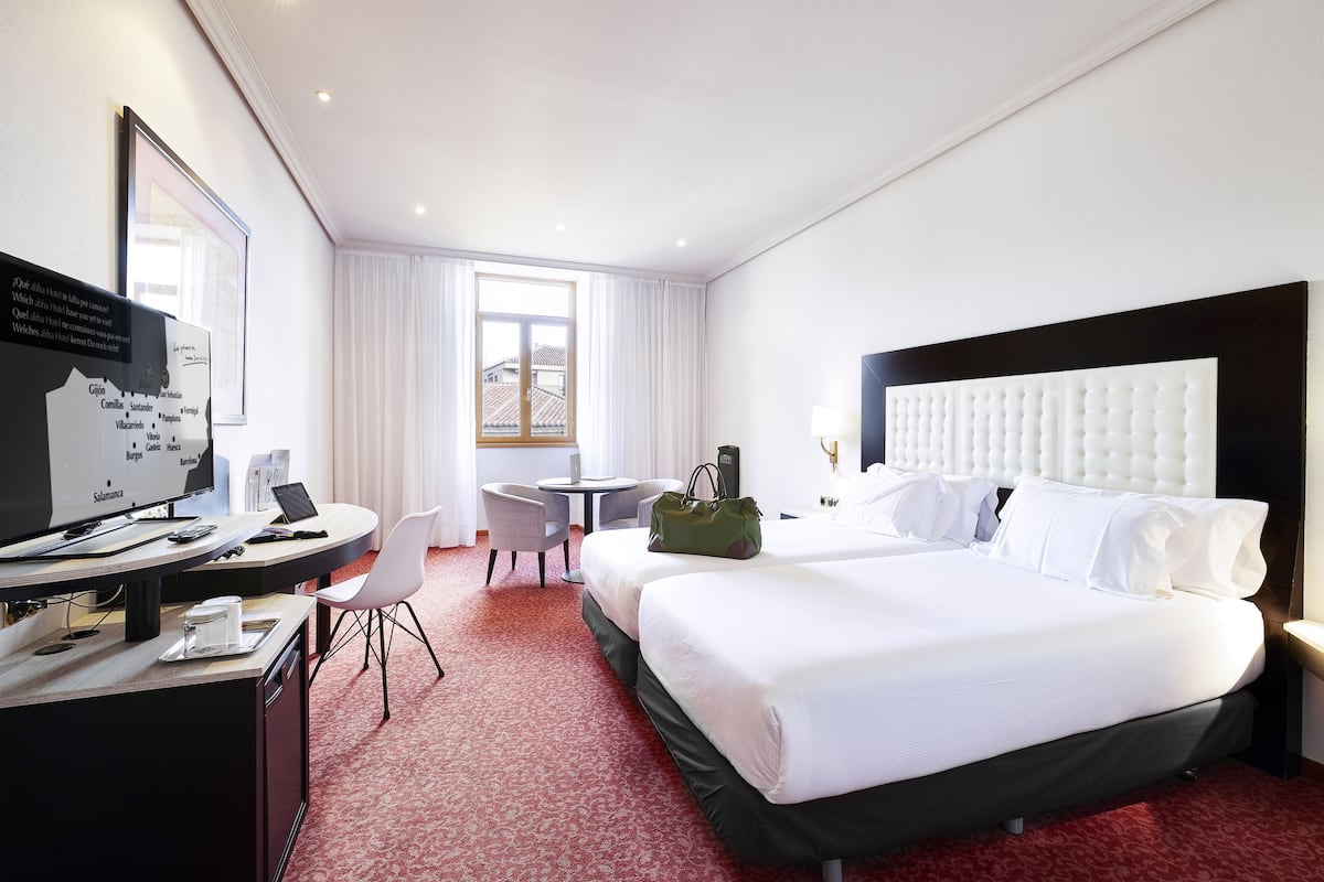 Une chambre d’hôtel avec un grand lit, un bureau avec un ordinateur, une chaise et une petite table.