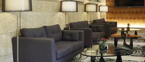 A modern lounge area with sofas, a flat-screen TV, and ambient lighting.