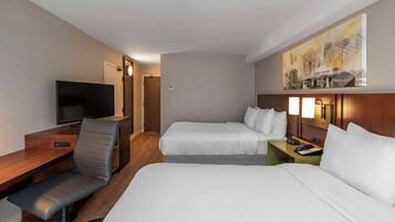 Une chambre d’hôtel avec deux lits, un bureau avec une chaise, une télévision et un tableau au mur.