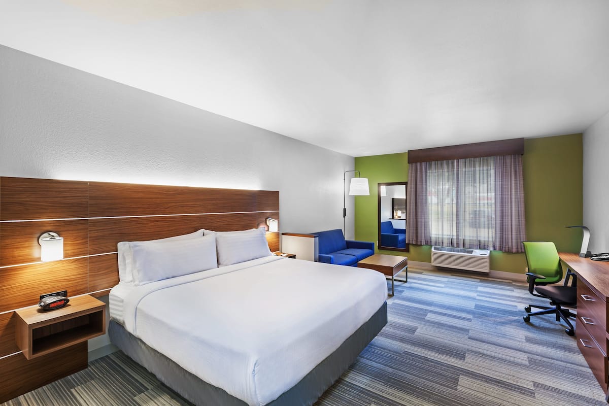 Una habitación de hotel con una cama grande, un escritorio, una silla y una mesita.