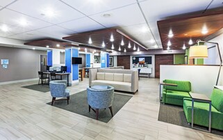 Um lobby moderno com áreas de estar, balcão de recepção e posto de informática.