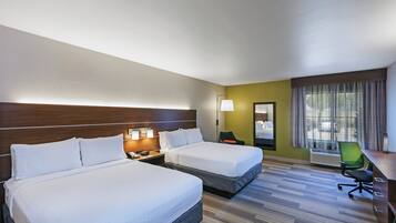 Une chambre d’hôtel avec deux lits, un bureau, une chaise, un miroir et une fenêtre avec des rideaux.