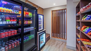 A vending area with various drinks and snacks, including soda cans and bottled water. - Holiday Inn Express Hotel & Suites Dallas Lewisville by IHG (Lewisville)