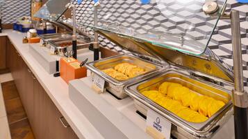 Indulge in a diverse selection of dishes at our buffet, featuring multiple serving stations with clear glass covers and stainless steel utensils.