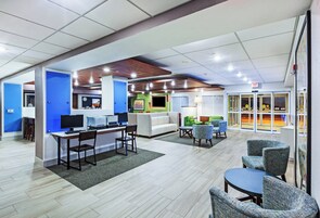 A spacious lobby with a reception desk, seating area, and a glass door leading to an indoor pool.