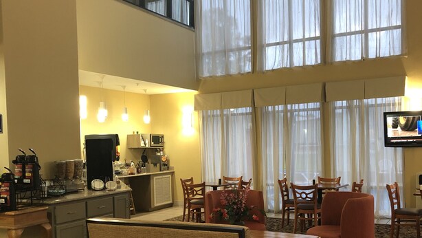 A hotel lobby with a dining area, kitchen, and large windows.