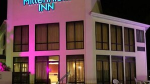 A Millennium Inn hotel with a pool, large windows, and a neon sign.