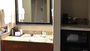 A bathroom with a sink, mirror, and a microwave.